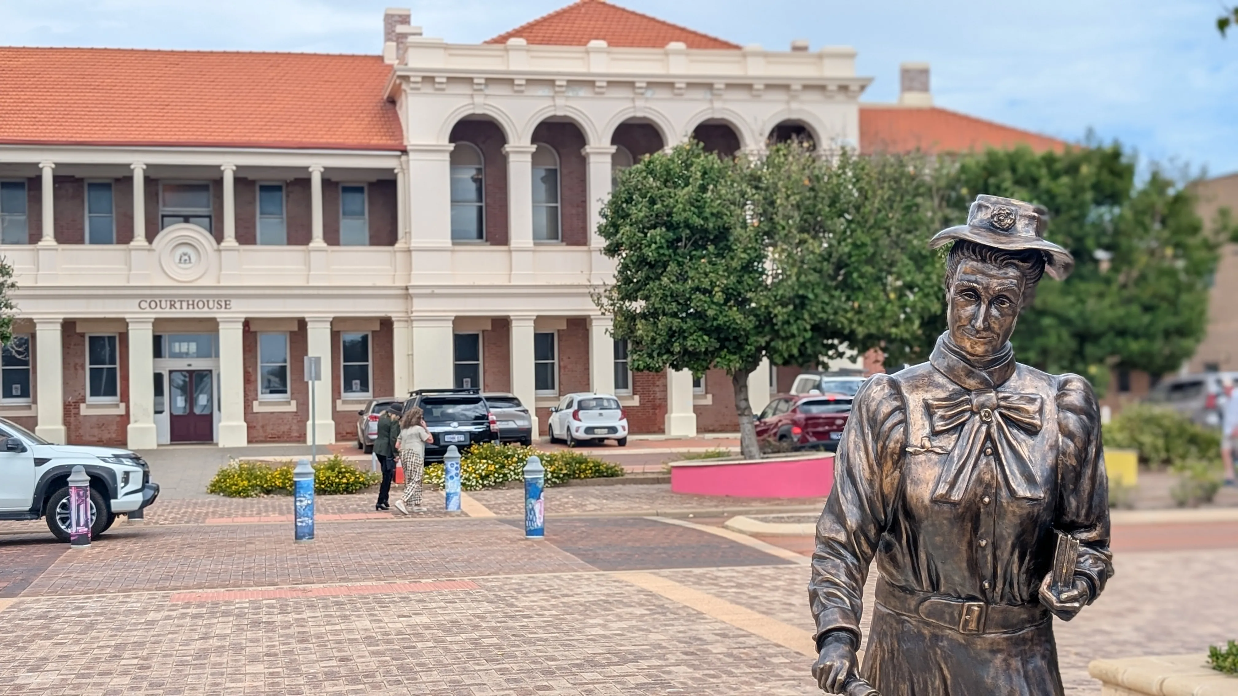 A photo of a statue of a lady in front of a building that says COURTHOUSE
