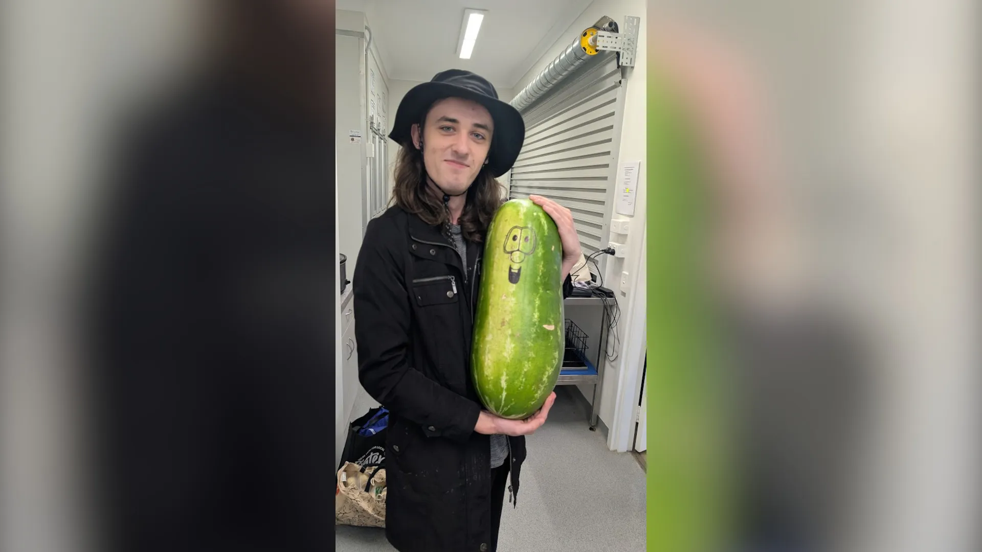 A photo of a person holding a watermelon with a face drawn on it.