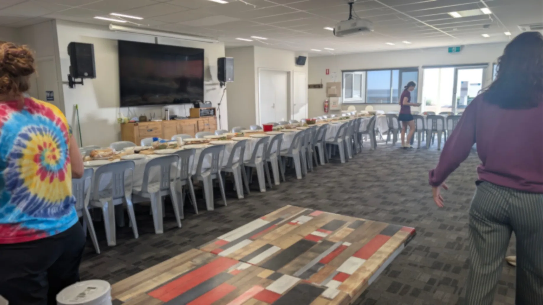 A photo of a long table with loads of chairs. The tables are decorated with plates, candles, and food.
